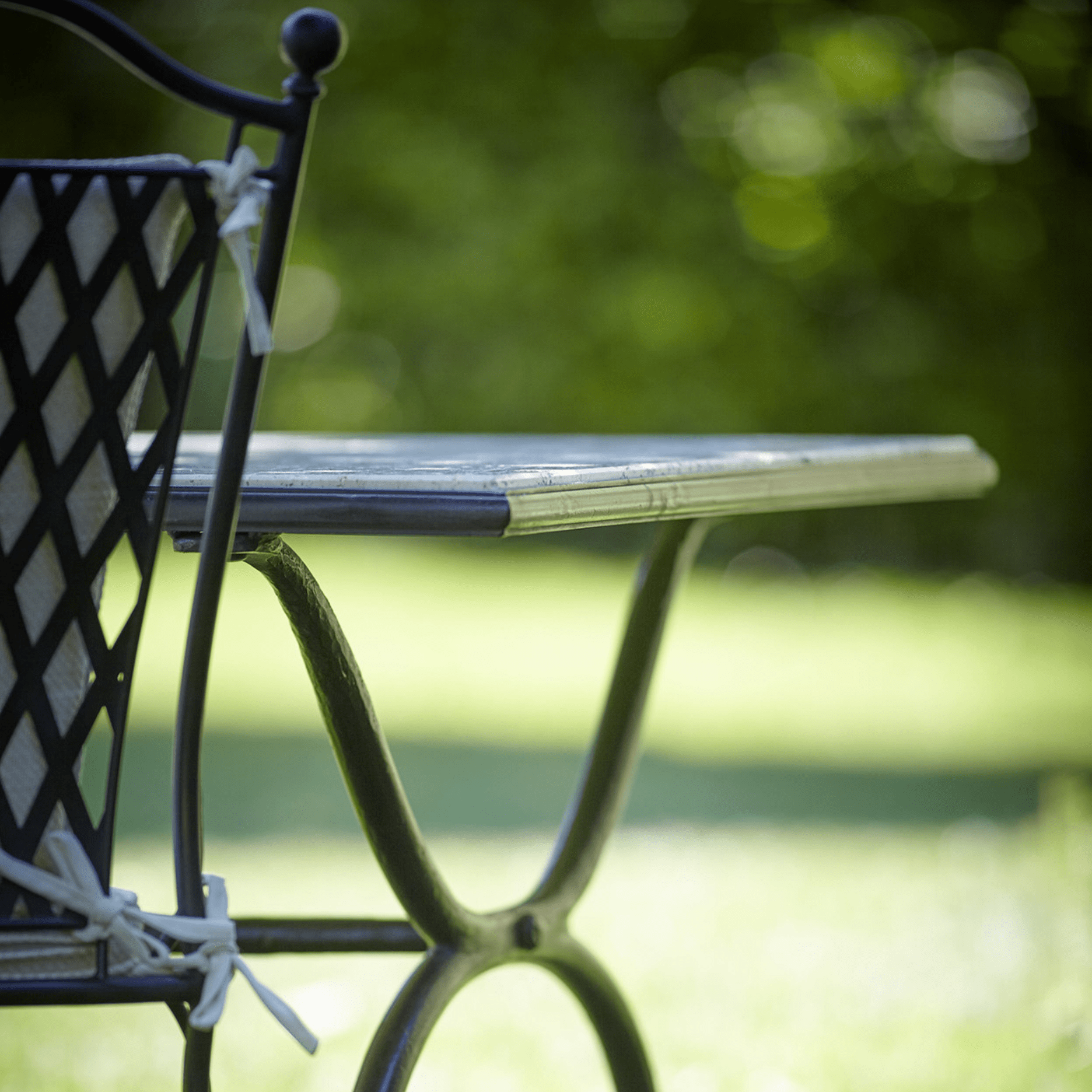 Close-Up of Classic Metal Lattice Dining Chair Backrest and Table | Luxury Outdoor Dining Furniture | Weather-Resistant Iron Design.