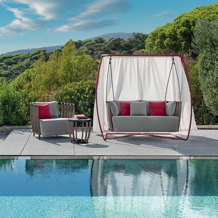 Luxury standalone porch sofa swing with matching outdoor armchair and coffee table, set by the pool | High-End Outdoor Living | Designed and Made in Italy | Ethimo Swing